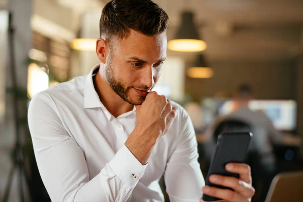 homem sorrindo com celular na mão